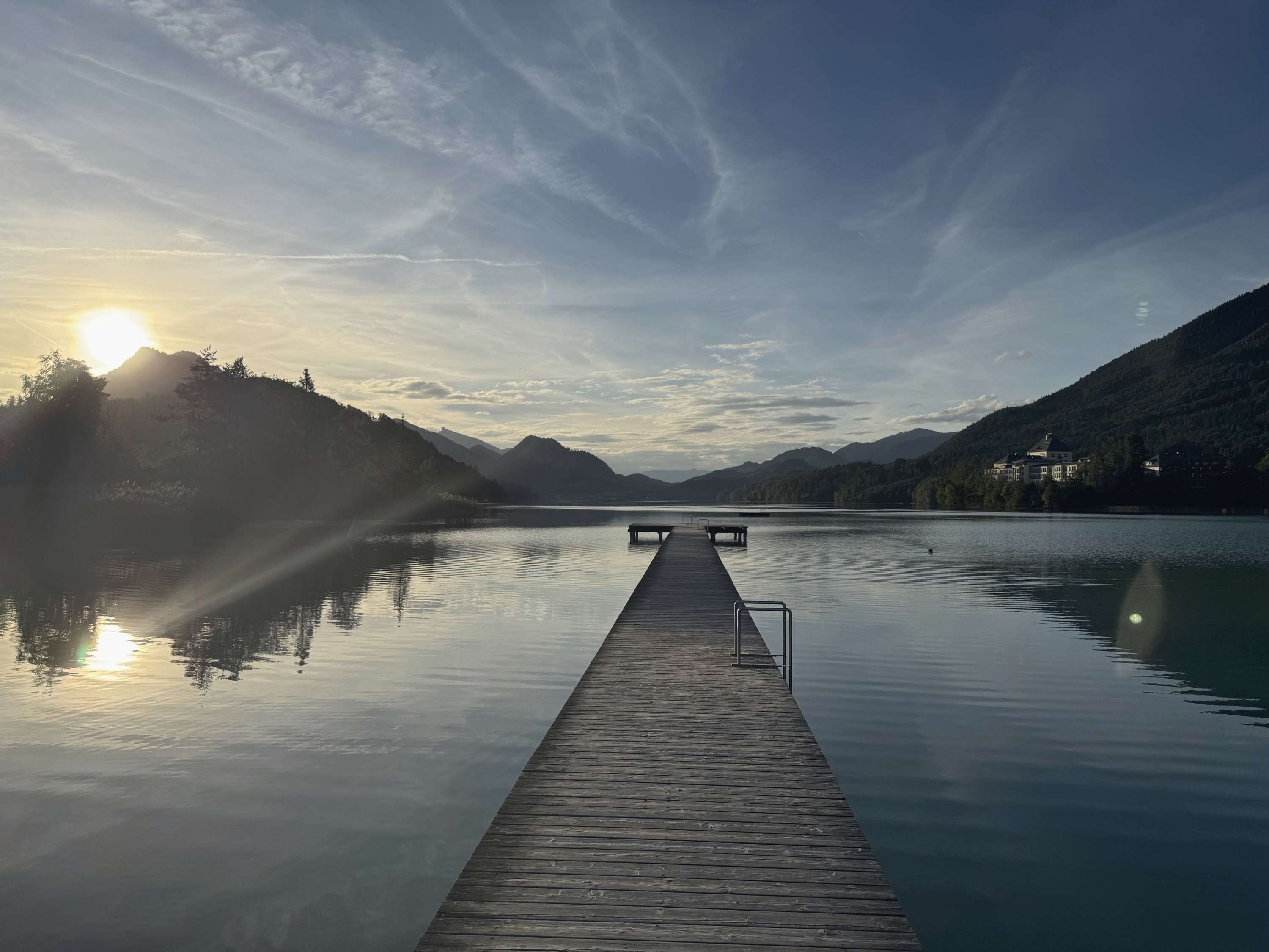 Ponton de lemn care intră într-un lac de munte, în zori