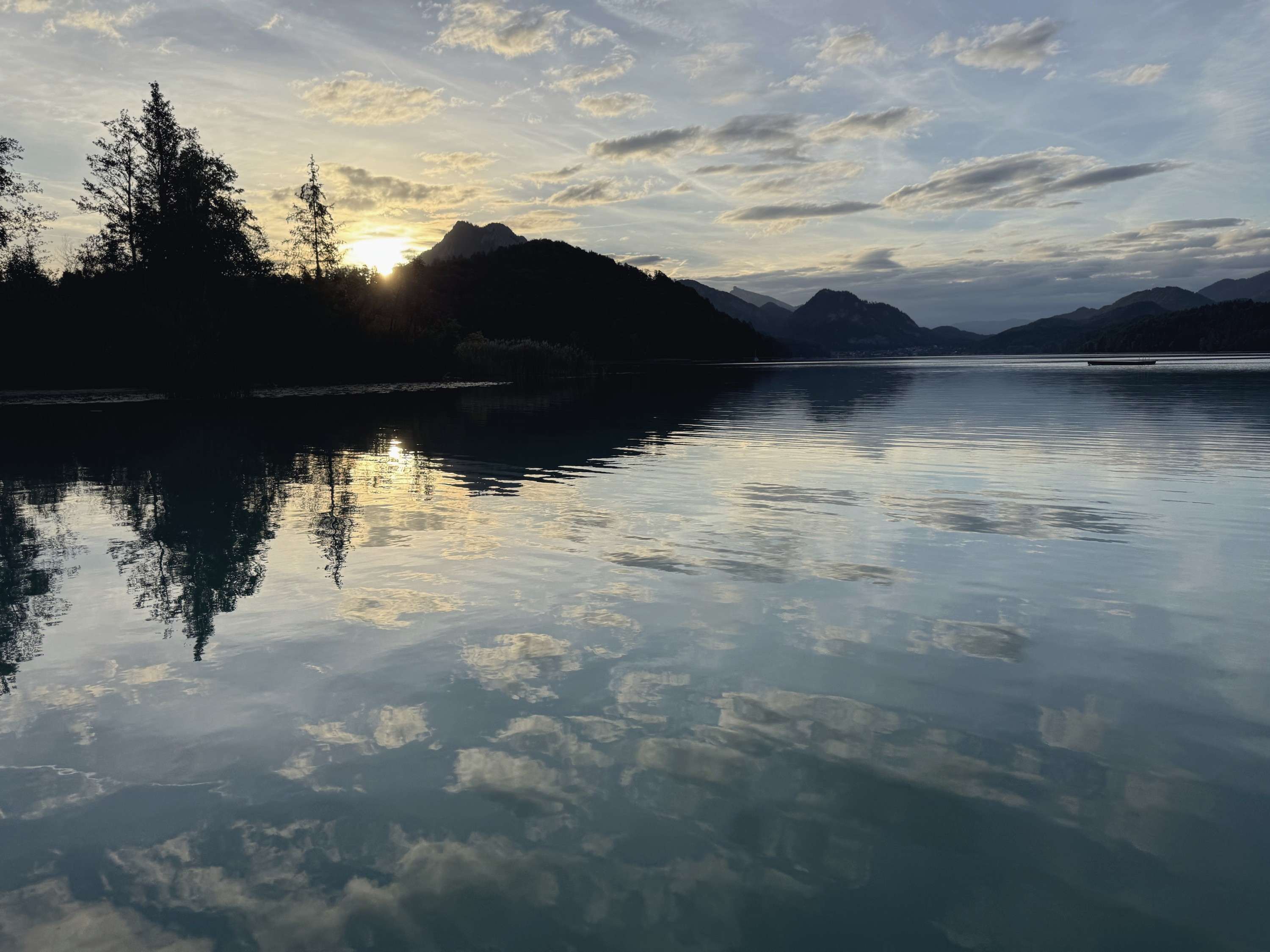 Lac de munte: norii și pădurea se oglindesc în apa liniștită